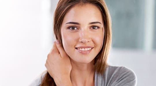 Smiling woman touching her hair, soft background.