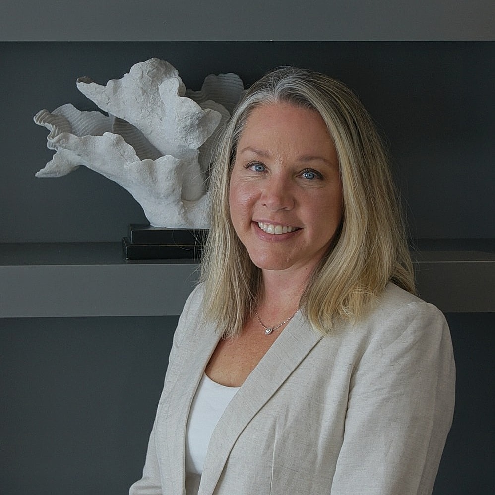 Woman smiling in professional attire with sculpture.