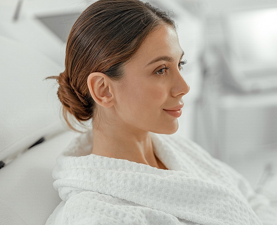 Woman in spa robe smiling serenely at camera.