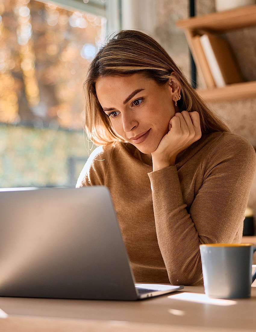 Woman working on laptop in cozy setting.
