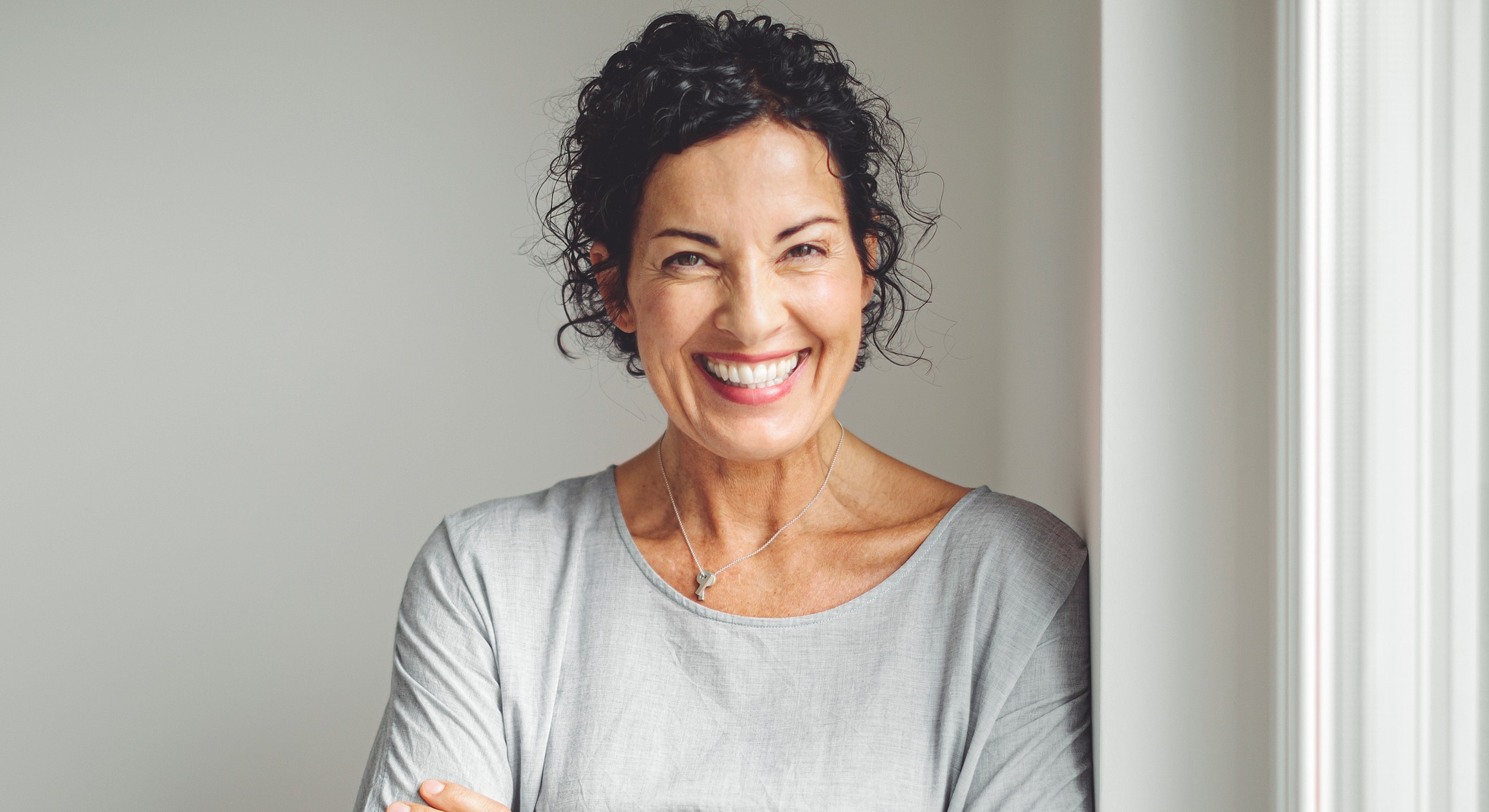 Roswell Sculptra model with curly hair in gray top.